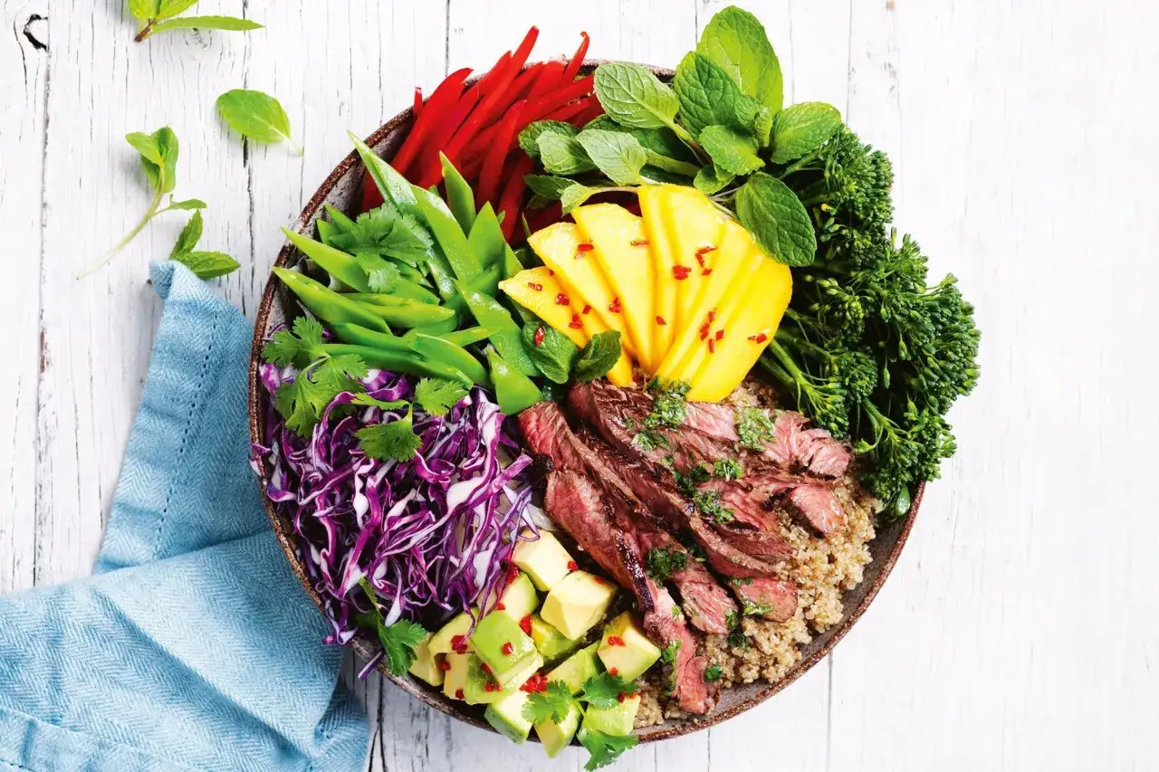 En färgstark skål med grillad biff, quinoa, mango, avokado, rödkål, sockerärtor, paprika och broccoli. En modern twist på klassiska sallader.