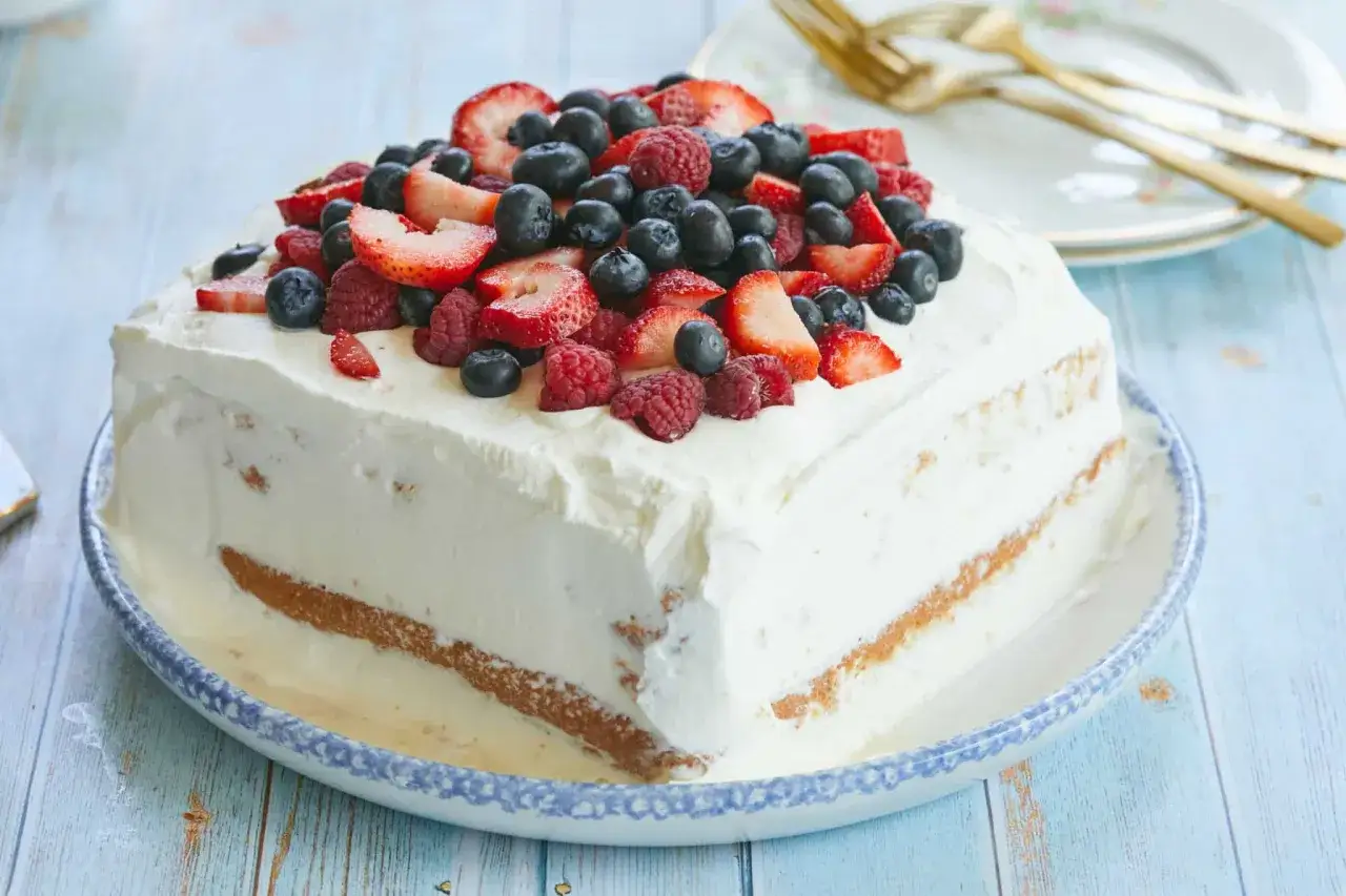 En krämig tres leches-tårta toppad med färska bär, perfekt för en sommarfest.