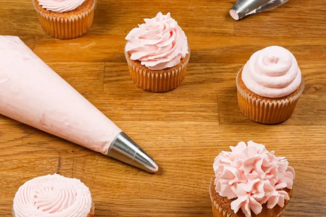 Färgglada cupcakes med rosa frosting, redo att dekoreras. Perfekt för att baka med Philadelphia!