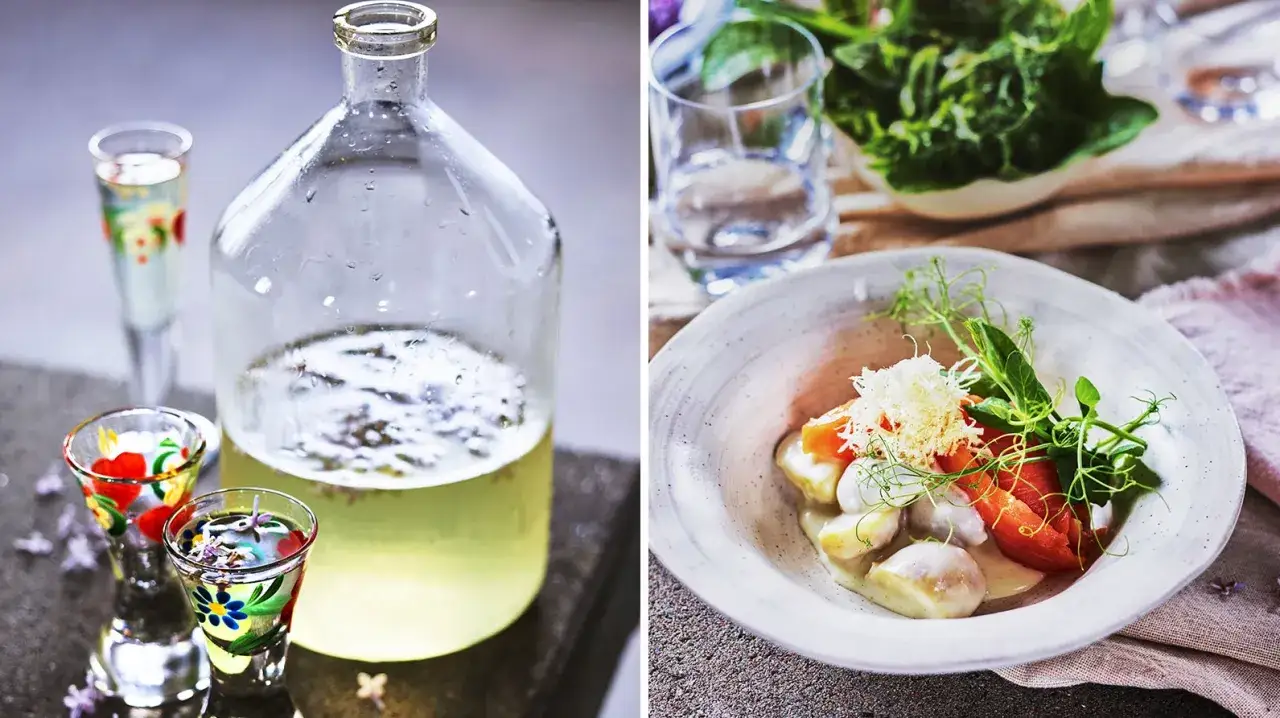 En flaska med ljusgul dryck och små, målade shotglas. Bredvid en skål med gnocchi, tomat och gröna skott, perfekt för en midsommar buffe.