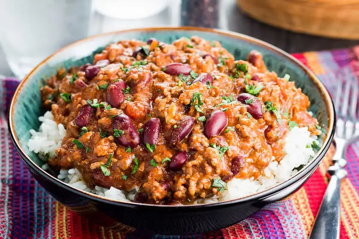 En skål med fluffigt ris toppad med en mustig chili con carne med bönor och köttfärs, garnerad med persilja. En perfekt middag!