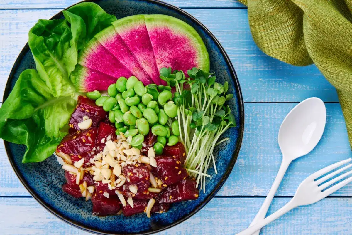En färgglad poke bowl med rå lax, edamamebönor, vattenmelonrädisa, groddar och sallad. Ett perfekt poke bowl recept för en hälsosam lunch.
