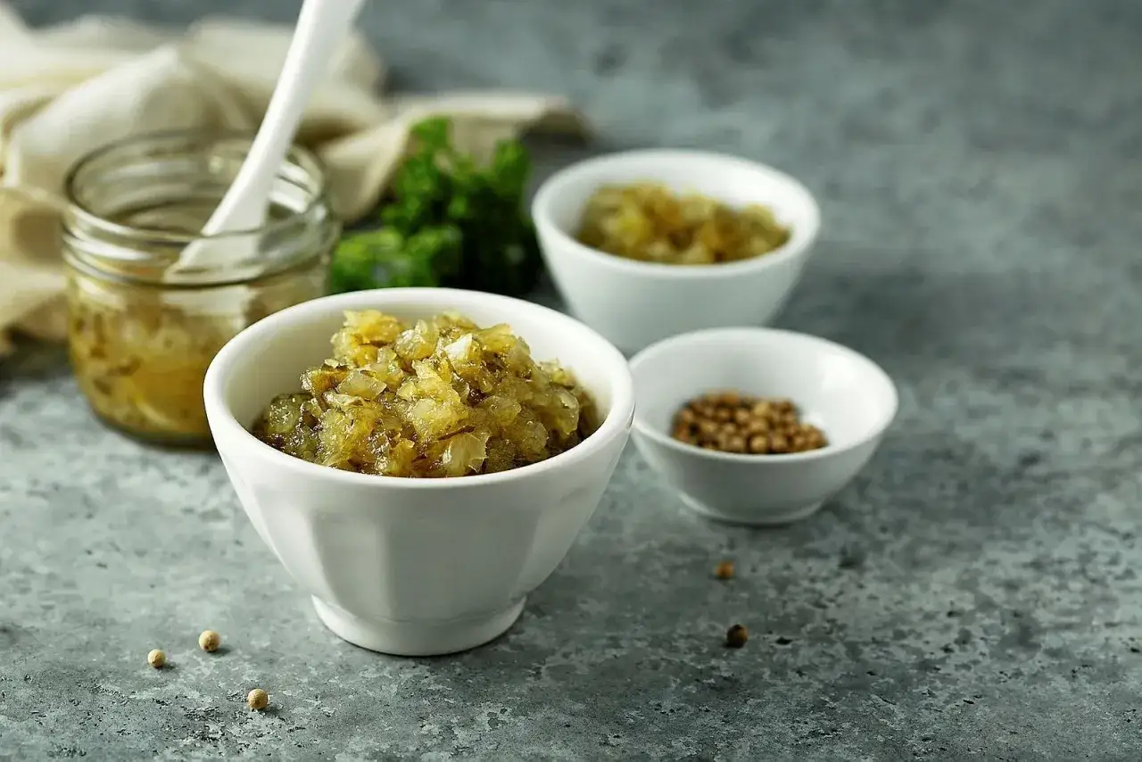 En skål med bostongurka, perfekt för ditt nästa bostongurka recept. Bredvid syns en burk med gurkan och en skål med senapsfrön.