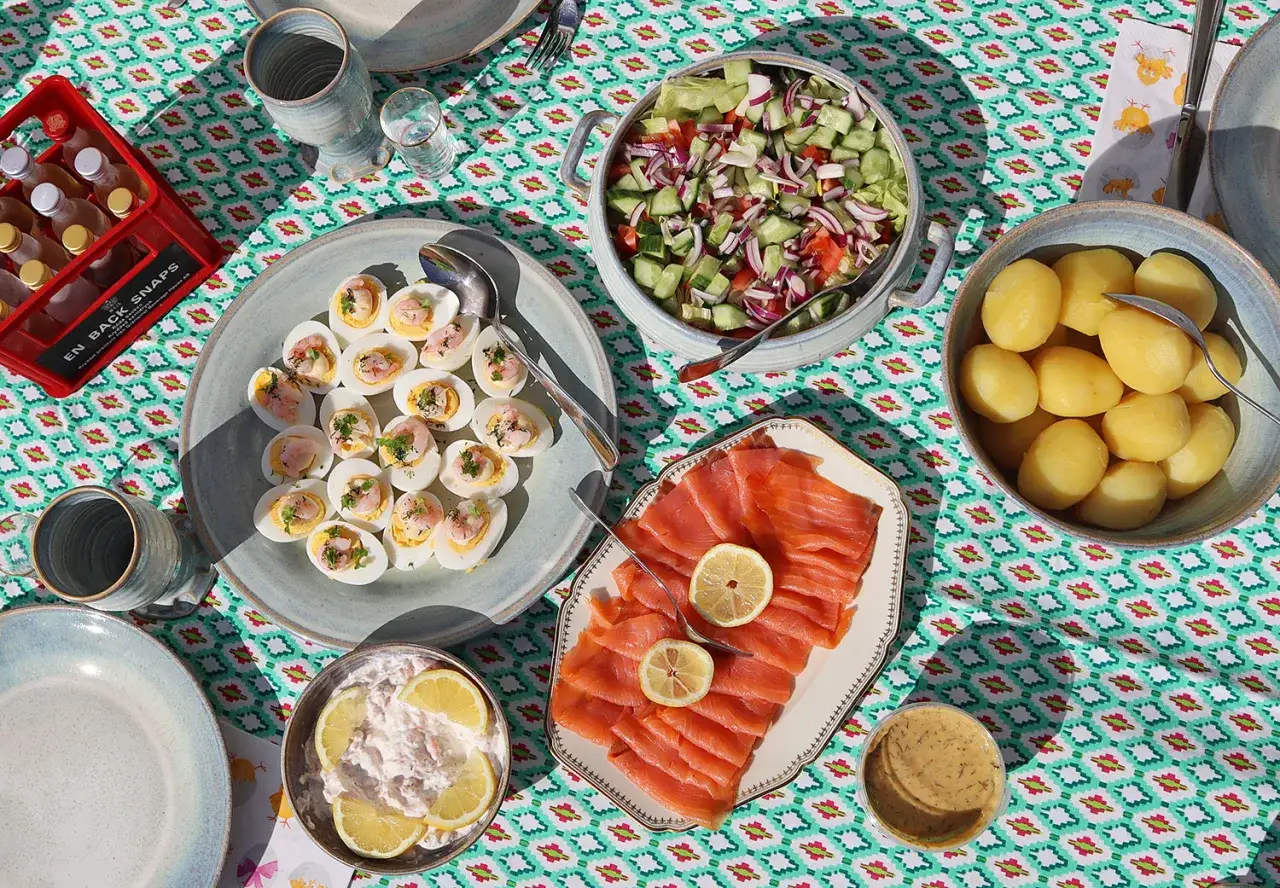 Ett härligt påskbord med mat som fyllda ägg, lax, potatis, sallad och en krämig röra. Perfekt för en festlig sammankomst.