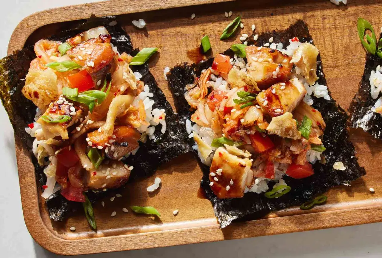 Asiatisk tacos med ris, kimchi och kyckling på noriark, strödd med sesamfrön och salladslök.
