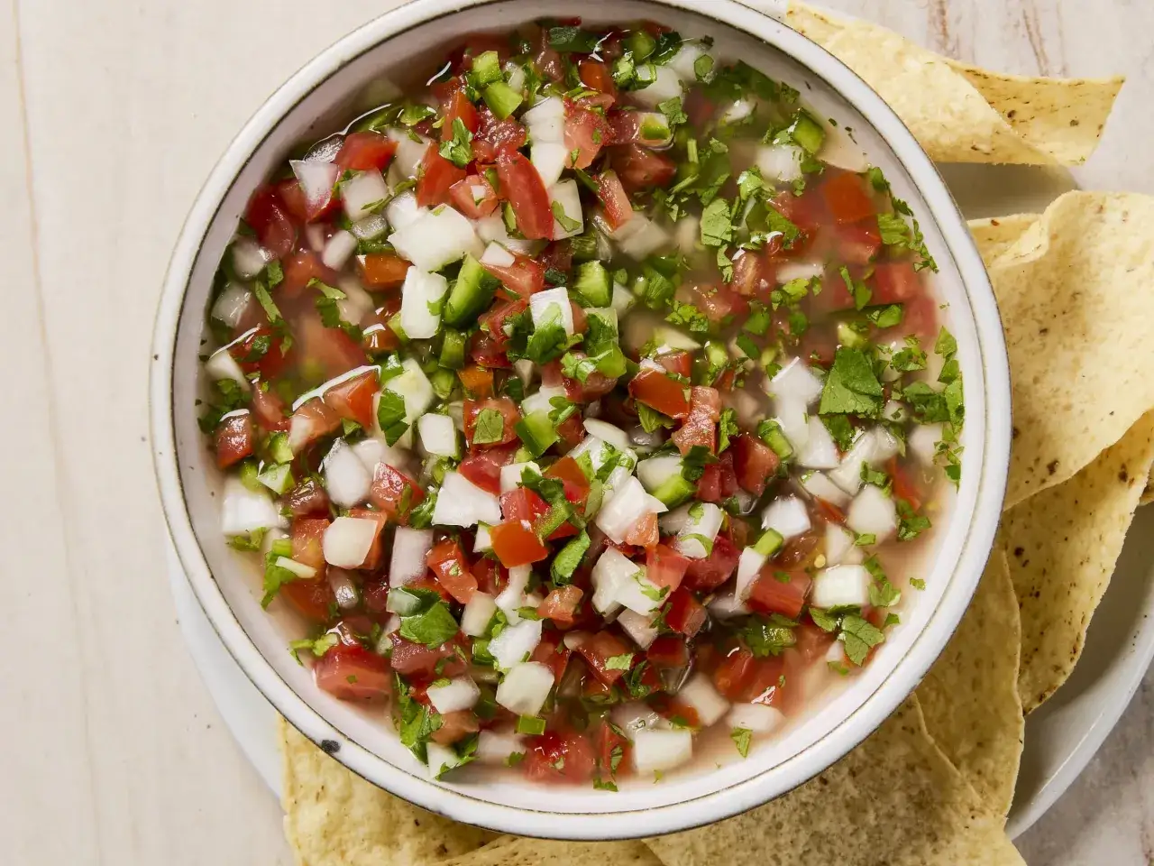 En skål med färsk pico de gallo, full av tärnad tomat, lök, jalapeño och koriander, serveras med tortillachips.