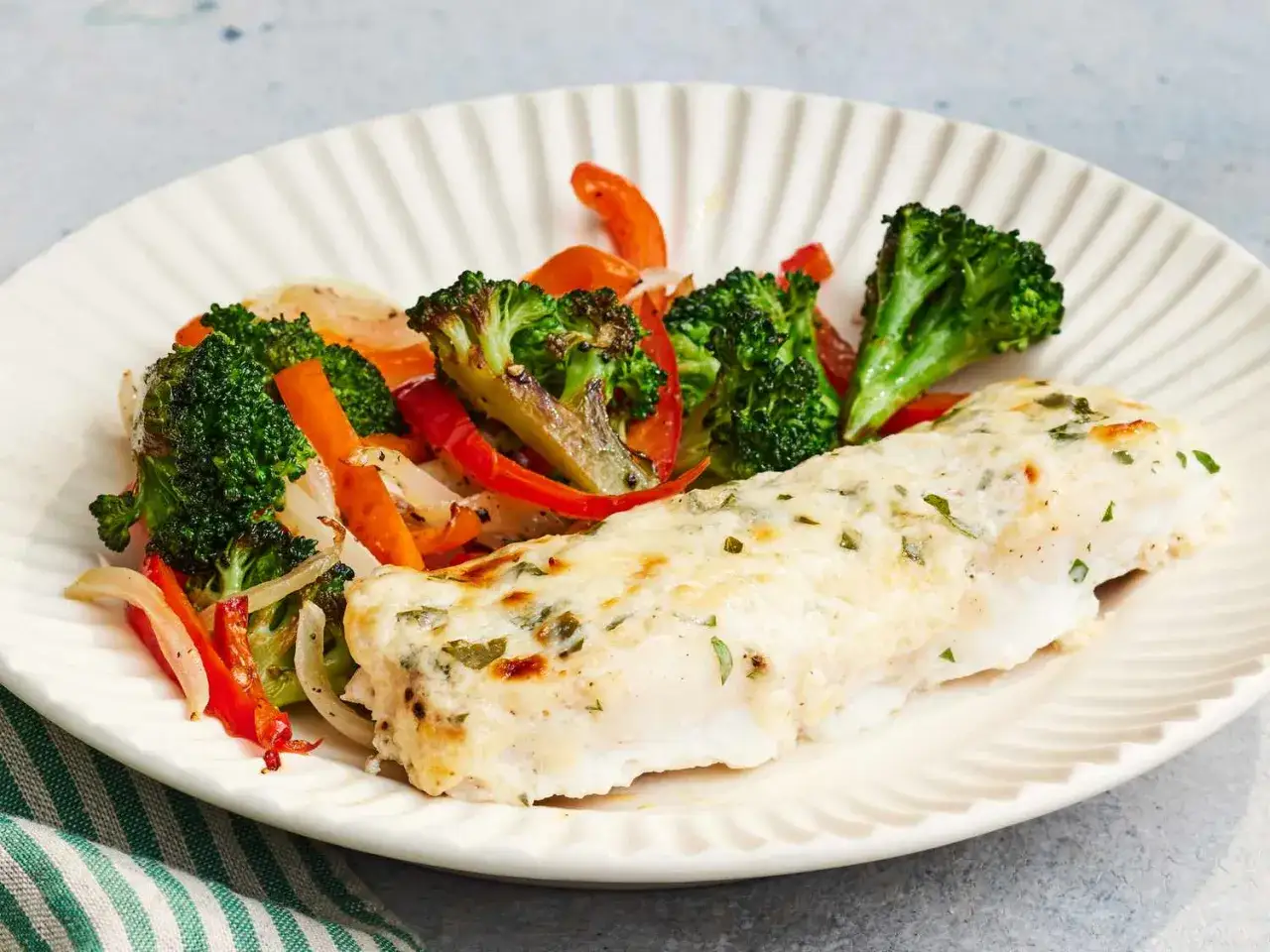 Ugnsbakad alaska pollock med ost och örter, serverad med rostade grönsaker som broccoli, paprika och lök. Ett enkelt och gott alaska pollock recept.