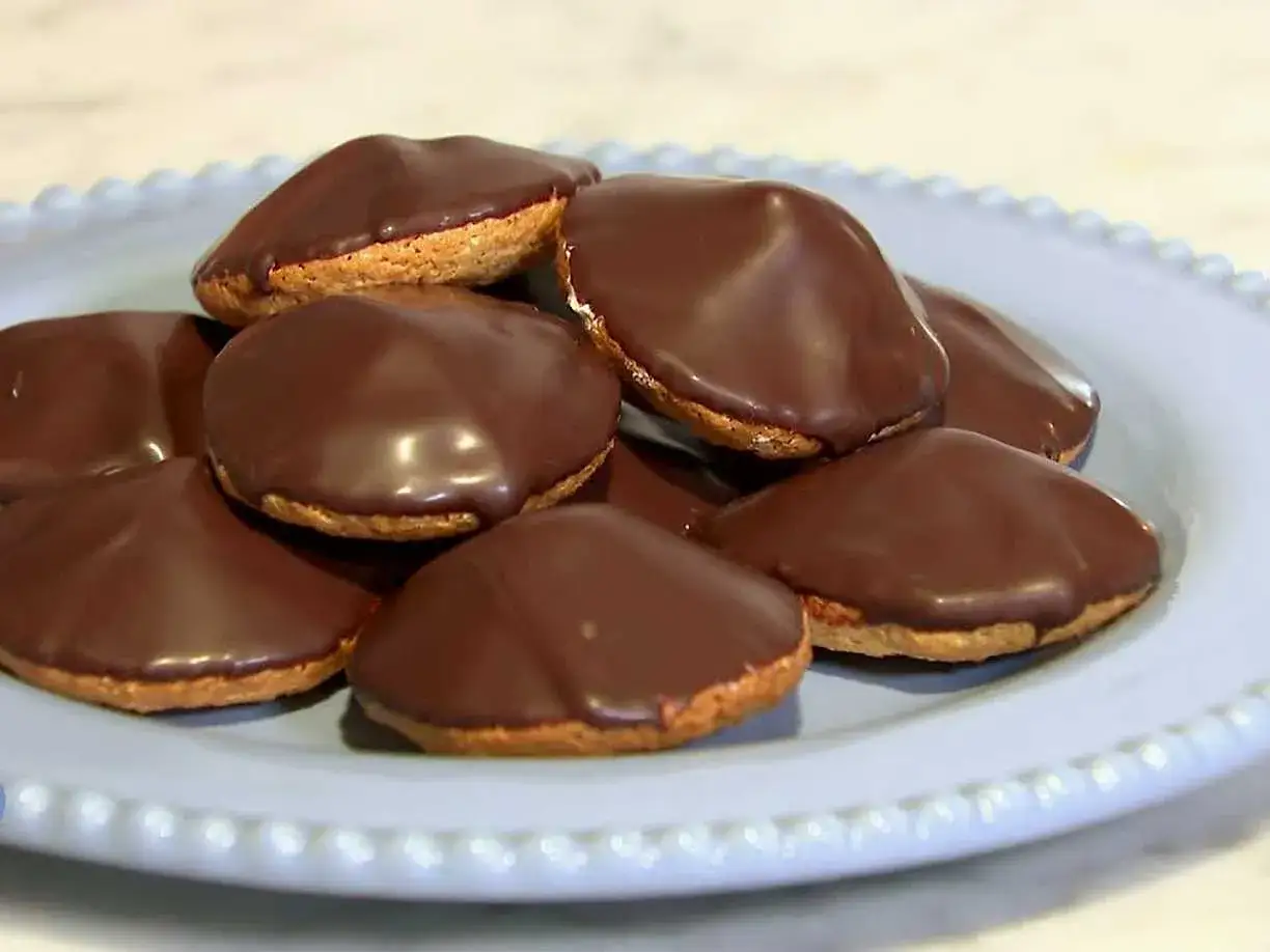 En h&ouml;g med choklad&ouml;verdragna biskvier p&aring; en ljusbl&aring; tallrik. Perfekt f&ouml;r ett enkelt biskvier recept.