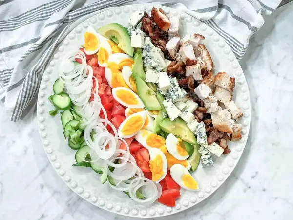En vacker cobb salad med kyckling, bacon, ägg, avokado, tomat, gurka, lök och blåmögelost.
