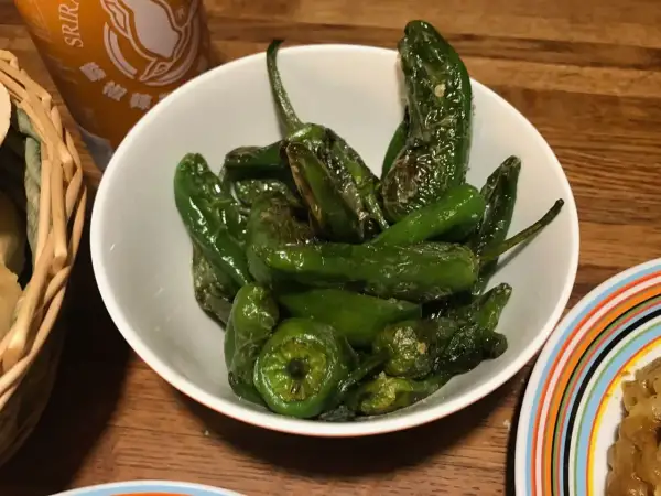 En skål med stekta pimientos de padron, glansiga och gröna, redo att avnjutas.