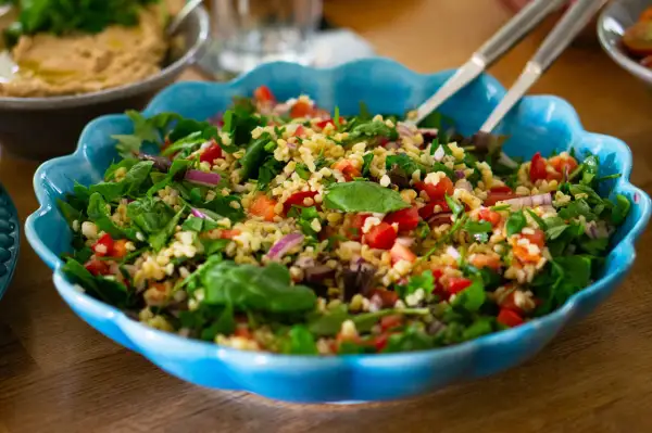 En fräsch tabbouleh med bulgur, tomater, lök och örter i en blå skål. Perfekt för ett lätt lunchrecept.