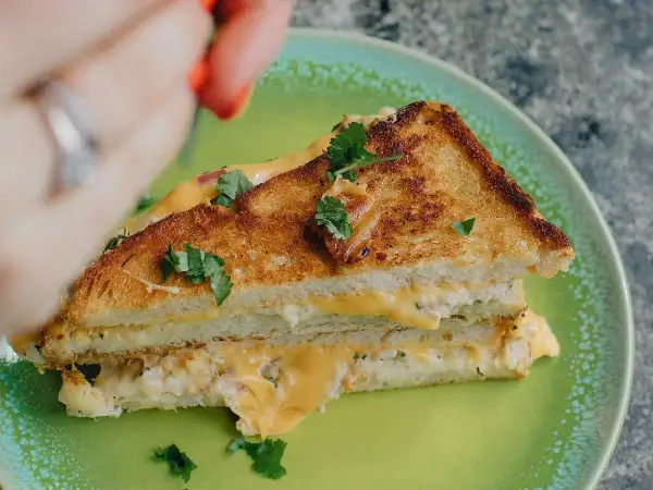 En gyllene, krispig tuna melt med smält ost och färska örter på en grön tallrik.